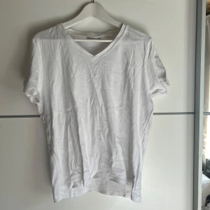 Vit v-ringad t-shirt från Isolde - Klassisk vit t-shirt från Isolde i storlek XL. T-shirten har v-ringning och korta ärmar, perfekt basic-plagg till garderoben. Tillverkad i mjuk bomull som känns skön mot huden. Enkel och stilren design som funkar till allt.