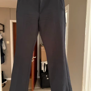 Svarta kostymbyxor med raka ben - Säljer dessa snygga svarta kostymbyxor med raka ben och klassisk passform. Byxorna har hällor för bälte och sidfickor, perfekta för en kväll ute men också till vardags! Tyvärr är de för små för mej och det är den enda anledningen till varför de säljs. Det finns inga anmärkningar på de och är väldigt sköna på. 