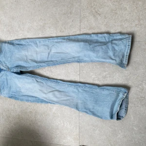 Bootcut ljusblå jeans från H&M - Bootcut jeans i ljusblå denim från H&M. Modellen har låg midja och justerbar midja för perfekt passform. Klassisk femficksdesign och raka ben som slutar i en lätt utsvängd bootcut. Perfekta för en avslappnad och trendig look.