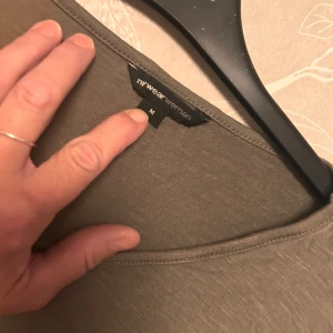 Olivgrön blus med vit nederdel MyWear - Säljer en olivgrön blus från MyWear Woman i storlek M. Toppen har v-ringning, korta ärmar och en snygg vit, transparent nederdel som ger en lager-på-lager känsla. Perfekt för dig som gillar en avslappnad men ändå stilren look.