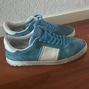 Ljusblå Valentino Flycrew  - Snygga sneakers i blå mocka och vitt skinn från Valentino. Saknar några nitar, typ 2-3 per sko. Mockan är lite skadad, priset är inte hugget i sten skriv vid frågor😁.endast skor medföljer