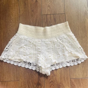 Vita spetsshorts - Superfina vita shorts med bred resår i midjan och detaljerad virkad spets över hela plagget.