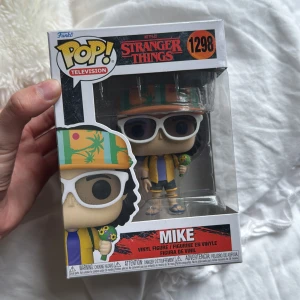 Stranger Things: Mike (Funko Pop! #1298) - Cool Funko Pop! vinylfigur av Mike från Stranger Things, perfekt för fans av serien. Med färgglad semesteroutfit, solglasögon och detaljerad design – en samlarfavorit för dig som älskar popkultur och unika figurer. Pris kan diskuteras!
