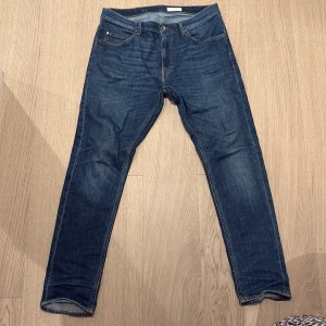 Tiger of Sweden jeans  - Snygga blå jeans från Tiger of Sweden med klassisk femficksdesign och raka ben. Jeansen har en mörk tvätt med lätt slitning och orange sömmar. Perfekta för dig som gillar stilrena och tidlösa jeans i bomull.