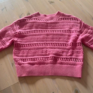 Rosa stickad tröja med hålmönster - Säljer en rosa stickad tröja med snyggt hålmönster och ribbade muddar😊. Tröjan har lång ärm och en lite boxig, croppad passform. Perfekt för dig som vill ha en färgglad och trendig look till våren eller hösten🫶🏻. Tröjan har används lite men är som ny💓