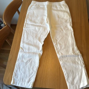 Vita linnebyxor från H&M, regular fit - Snygga vita linnebyxor från H&M i regular fit. Byxorna har resår i midjan, raka ben och sidfickor samt en bakficka. Perfekta för varma dagar och chill vibes. Luftigt material som känns fräscht och stilrent. Stl M                              Hör gärna av er vid frågor