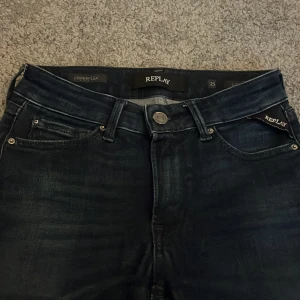 Mörkblå Replay Hyperflex jeans - Snygga mörkblå Replay Hyperflex jeans med klassisk femficksdesign och diskreta slitningar. Jeansen har normal passform och är tillverkade i stretchigt jeansmaterial för extra komfort. Perfekta för dig som gillar stilrena och bekväma jeans.