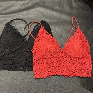 Spetsiga bralettes i svart och rött - Två snygga bralettes med blommig spets, en i svart och en i rött. Båda har tunna axelband och v-ringad form, perfekta att styla under en öppen skjorta eller kavaj. De är ärmlösa och har fina detaljer i spets som ger en romantisk vibe.