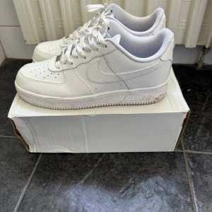 Nike Air Force 1  - Strl 43. Fint skick. Bara använda ca 10 gånger. Klassiska Nike Air Force 1 sneakers i helvitt skinn med perforerad tå, vit sula och snörning. Snygg och tidlös modell som passar till allt, med låg profil och ikonisk swoosh på sidan. Perfekta för dig som gillar clean och stilren streetwear.