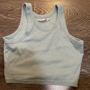 Ljusblå ribbad linnetopp från 157 - Snygg ljusblå ribbad linnetopp från 157. Toppen är ärmlös med klassisk rund halsringning och croppad passform. Perfekt att matcha med jeans eller shorts för en chill look.