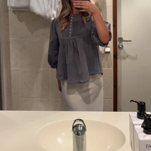 Blå blus med knappar och vida ärmar - Säljer en lös och luftig blå blus med dekorativa knappar framtill och trekvartsärmar. Blusen har en avslappnad passform och lätt rynkade detaljer under bysten. Perfekt för dig som gillar en chill och stilren look. Storlek M men sitter som S