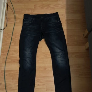 G-Star Raw Revend Super Slim jeans - Mörkblå jeans från G-Star Raw, modell Revend Super Slim. Snygg, smal passform med klassiska fem fickor och diskreta slitningar framtill. Jeansen är tillverkade i stretchigt denim för en bekväm känsla och har en modern look.