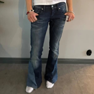 Mörkblå bootcut jeans med slitningar - Snygga mörkblå bootcut jeans med slitningar och ljusare partier framtill. Jeansen har dekorativa sömmar på bakfickorna och silverfärgade knappar. Midjemått: 36cm, innerben: 77,5 💕 De kan vara lite slitna nedtill eftersom de är omsydda men de är fortfarande funktionella och det går att sy om om man vill!