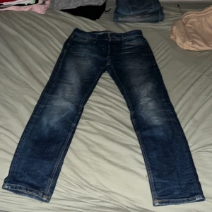 Blå jeans från Jack & Jones - Säljer ett par klassiska blå jeans från Jack & Jones med snygg tvätt och raka ben. Jeansen har fem fickor, normal passform och är tillverkade i slitstarkt denim. Perfekta för dig som gillar en enkel och tidlös stil.