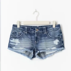 Lågmidjade slitna jeansshorts - Snygga lågmidjade jeansshorts i blå denim med slitna detaljer, Perfekta för varma sommardagar och ger en cool, avslappnad vibe. Helt nya med lappen kvar💕