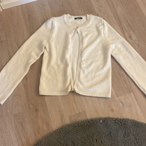 Beige kofta från Gina Tricot XS - Snygg beige kofta från Gina Tricot i storlek XS. Koftan har rund halsringning, lång ärm och ribbade kanter. Enkel och stilren design som är lätt att matcha med olika outfits. Perfekt för lager-på-lager under kyligare dagar. Säljer då den aldrig kommer till användning. Helt oanvänd. 