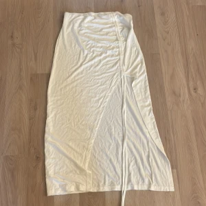 Vit kjol - Säljer min vita kjol med justerbar slits. Aldrig använd då den är för lång. Är i storlek M men passar mig som är xs. Väldigt stretchig så passar även L