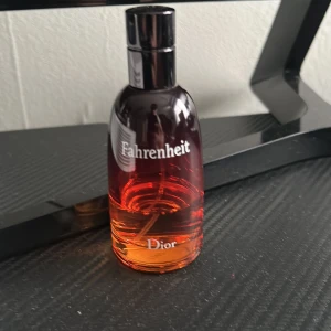 Dior Fahrenheit parfym 100ml - Dior Fahrenheit parfym i en snygg glasflaska med röd till orange gradient. Flaskan har rundad form och svart kork. Klassisk doft med maskulina och varma toner, perfekt för dig som gillar ikoniska parfymer.