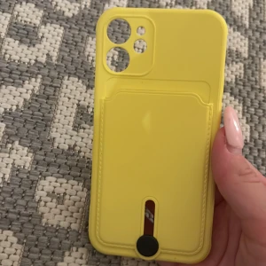 Gult mobilskal med kortfack - Detta stilrena mobilskal skyddar inte bara din telefon från repor och stötar, utan har även ett praktiskt fack för dina viktigaste kort. Perfekt för dig som vill resa lätt och ha allt du behöver på ett ställe. 