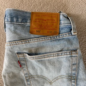 Levi's 501 ljusblå jeans W32 L32 - Klassiska Levi's 501 jeans i ljusblå tvätt med raka ben och femficksmodell. Jeansen har hög midja, knappgylf och tydliga kontrastsömmar. Tillverkade i slitstarkt bomullsjeans, perfekt för en avslappnad och tidlös stil.
