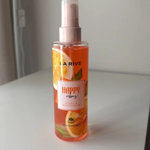 La Rive Happy Vibes Body Mist - Fräsch body & hair mist från La Rive med namnet Happy Vibes. Doften har inslag av apelsin och citrus, och innehåller vitamin E samt provitamin B5. Flaskan är genomskinlig med orange vätska och har en rosa spraykork. Vegansk formula.