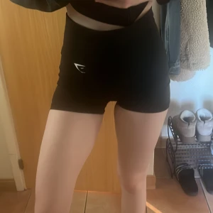 Träningsshorts - Gymshark - Svarta, åtsittande och högmidjade träningsshorts från Gymshark. Materialet är oerhört behagligt och stretchigt, perfekt för all typ av träning. OBS: Sömmen har gått upp lite, vilket kan ses på sista bilden. Men går lätt att åtgärda genom att sy igen🖤