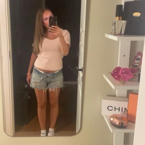Lågmidjade slitna jeansshorts från Zara - Säljer ett par ljusblå lågmidjade jeansshorts med fransig kant och slitna detaljer. Shortsen har en avslappnad loose fit och klassisk femficksdesign. Perfekta för sommardagar och ger en cool, avslappnad vibe.