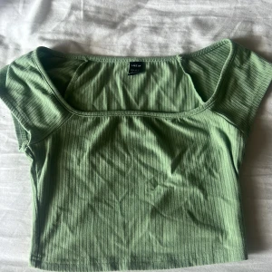 Grön ribbad topp från SHEIN - Snygg ljusgrön ribbad topp från SHEIN med fyrkantig ringning och korta ärmar. Toppen är croppad och har en tight passform som framhäver figuren. Perfekt att matcha med jeans eller kjol för en trendig look.