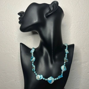 Vintage halsband med snäckskal och pärlor – turkost skimmer - 60-tal 70-tal  - Vintagehalsband i skimrande turkosa snäckskal och pärlemor, ca 54 cm långt. Inropat på auktion, troligen tillverkat i Asien på 60- eller 70-talet. Oregelbundna snäckor och mindre pärlor (0,5–1,7 cm) skapar ett organiskt, levande uttryck. Svalt mot huden med naturlig glans – perfekt till lager-på-lager eller som statement. Priset är redan lågt, så jag prutar inte – men ger rabatt vid köp av flera saker. Jag rensar garderoben – kika gärna på mina andra annonser!