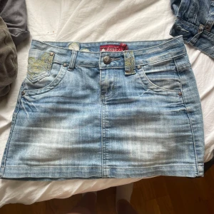Lågmidjad jeanskjol - Supersnygg jeanskjol, blivit för liten. Kedjan strular lite men annars helt felfri! Man kan ha öppen gylf och det kommer inte ens synas
