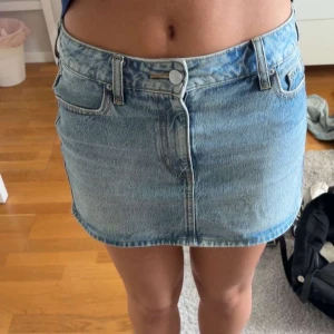Jeanskjol - Snygg ljusblå jeanskjol i kort modell med klassiska fem fickor, bälteshällor och knapp framtill. Perfekt för dig som gillar en enkel och tidlös stil. Kjolen har en rak passform och är lätt att matcha med allt. Köpt i usa från Pacsun för $60 (ca 600kr)