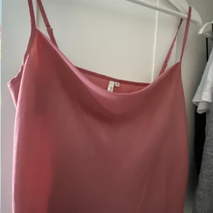 Rosa linnetopp med tunna axelband - Säljer en stilren rosa linnetopp  med tunna axelband och snygg draperad urringning. Perfekt att matcha med jeans eller kjol för en trendig look. Toppens material känns mjukt och svalt mot huden.