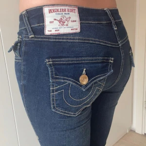 True Religion blå bootcut jeans - Säljer ett par blå jeans från True Religion med ikoniska bakfickor och guldiga knappar. Jeansmodellen är Joey mid-waist och storlek 24! 💗 Jätte fina och bekväma, dom kan också vikas ner i midjan för lägre midja! 