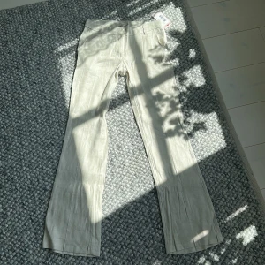 Beiga low waist bootcut linnebyxor från Nelly - Snygga beiga linnebyxor från Nelly med låg midja och utsvängda ben. Byxorna har ett lätt och luftigt linnematerial, perfekta för en sommar kväll för er som kanske gillar mer Stockholms stil. Passar till er som har 36 i byxor. Byxorna är ej använda 