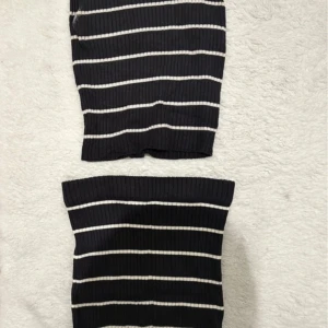 Svartvit randig ribbad kortkjol och linne  - Säljer en svart ribbad kortkjol med vita horisontella ränder. Kjolen är tight och har en stretchig passform som sitter snyggt på kroppen. Perfekt för dig som gillar en enkel men ändå trendig look. Det finns fläck under armhålan.