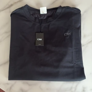 Svart t-shirt från ICANIWILL - Svart t-shirt från ICANIWILL med diskret broderad logga på bröstet. Klassisk rund halsringning och korta ärmar. Tillverkad i mjuk bomull som känns skön mot huden. Perfekt basic-plagg med clean look.