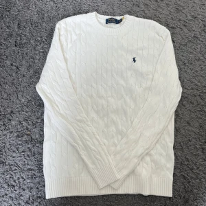 Vit stickad tröja Ralph Lauren - Storlek M. Vit kabelstickad tröja från Ralph Lauren med broderad svart logga på bröstet. Långärmad modell i mjuk bomull, perfekt för en clean och stilren look. Priset kan diskuteras.