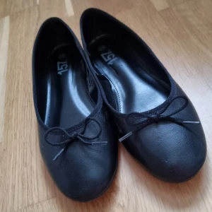 Svarta ballerinaskor med rosett - Klassiska svarta ballerinaskor från lager 157 med rund tå och liten rosett framtill. 💕Skorna har en platt sula och en liten klack. Har använt dem en gång men är för små. Dom har en liten repa på vänster sko på höger sida, som man ser på blid 3 men syns inte när dem är på. Det är storlek 39!💕 Jag står inte för frakt! 💕 ( kommer tvättas mer noga innan jag skickar dom! 💕) 