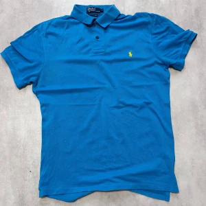 Blå pikétröja från Ralph Lauren - Blå pikétröja från Ralph Lauren ✅ Storlek: M ✅ Skick: Mycket bra (9/10)  ✅köpt för 800kr+Snygg och stilren piké med klassisk krage, två knappar framtill och broderad gul Polo-logga på bröstet. Perfekt för en avslappnad men uppklädd stil.  📩 Skriv i DM vid frågor eller om du vill förhandla priset!