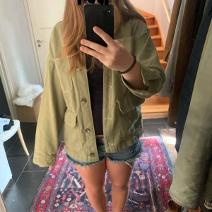Grön Jeansjacka - Jättefin jeansjacka i en khaki/grön färg. Väldigt bra skick förutom en liten fläck på ryggen som man inte lägger märke till. Supersöt som passar i hösten och våren men även på sommarn under de mindre varma dagarna. Storlek XS men rätt så oversized, passar mig som är 172 och bär M i överdelar.💕Buda gärna!!