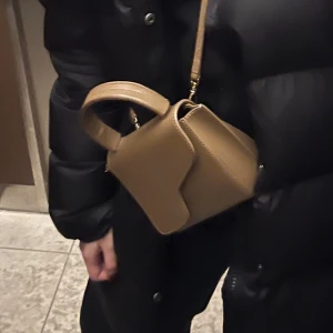 Beige mini handväska med axelrem - Liten ATP atelier väska i färgen brun. Superfint sick, kvitto finns! Inköpt på nk för 3900kr🥰