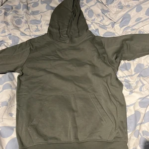 Grå hoodie från Kappahl - Säljer en enkel grå hoodie från Kappahl i storlek 158/164. Tröjan har en stor ficka framtill och huva. Perfekt för en avslappnad stil och passar till det mesta.