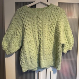 Ljusgrön stickad tröja med pärlor - Superfin ljusgrön stickad tröja med kortare ärmar och pärldetaljer. Tröjan har ett grovt kabelstickat mönster och bred ribbad kant vid hals, ärmslut och nederkant. Skriv privat för fler bilder 🩷