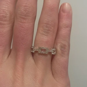 Silverfärgad ring med rektangulära länkar - Säljer ett stilrent silverfärgad ring  med rektangulära länkar och små gnistrande stenar. Perfekt för dig som gillar unika detaljer och modern design. Ringen är justerbar