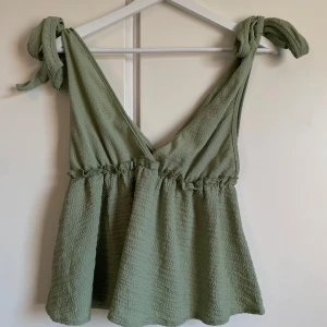 Ljusgrön topp med knytaxlar - Säljer en ljusgrön topp med djup v-ringning och knytband på axlarna. Mycket bra skick, endast använd 1 gång.