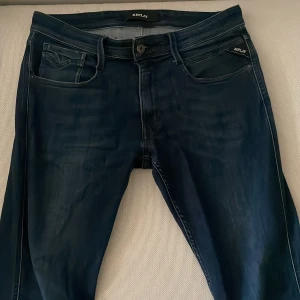 Replay anbass - Säljer ett par mörkblå Replay Hyperflex jeans med klassisk smal passform. Jeansen har stretchigt material för extra komfort och subtila slitningar framtill. Perfekta för dig som gillar stilrena och bekväma jeans. 