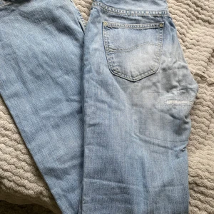 Ljusblå jeans från Lee - Säljer ett par klassiska ljusblå jeans från Lee med bootcut. Jeansen Lee-logga på bakfickan samt läderpatch i midjan.