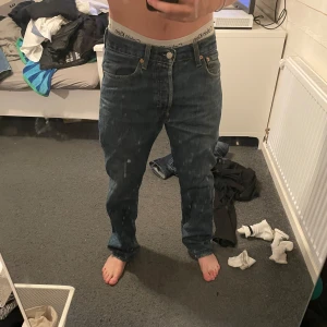 Levi's 501 jeans blå W31 L30 - Klassiska blå Levi's 501 jeans med raka ben och knappgylf. Jeansen har fem fickor och den ikoniska läderpatchen bak i midjan. Passar dig som gillar en tidlös och avslappnad stil. Midjemått W31 och benlängd L30.