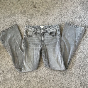 Grå bootcut jeans från Gina Tricot - Snygga grå jeans från Gina Tricot i bootcut-modell. Jeansen har klassisk femficksdesign, knapp och dragkedja framtill samt raka ben som blir vidare nedtill. Skriv privat om du har frågor! Midjemåttet är 33 rakt över💕