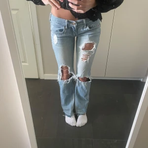 Ljusblå low waist bootcut jeans - Skitsnygga blåa low waist bootcut jeans med slitningar. Otroligt snygga och i väldigt bra skick.